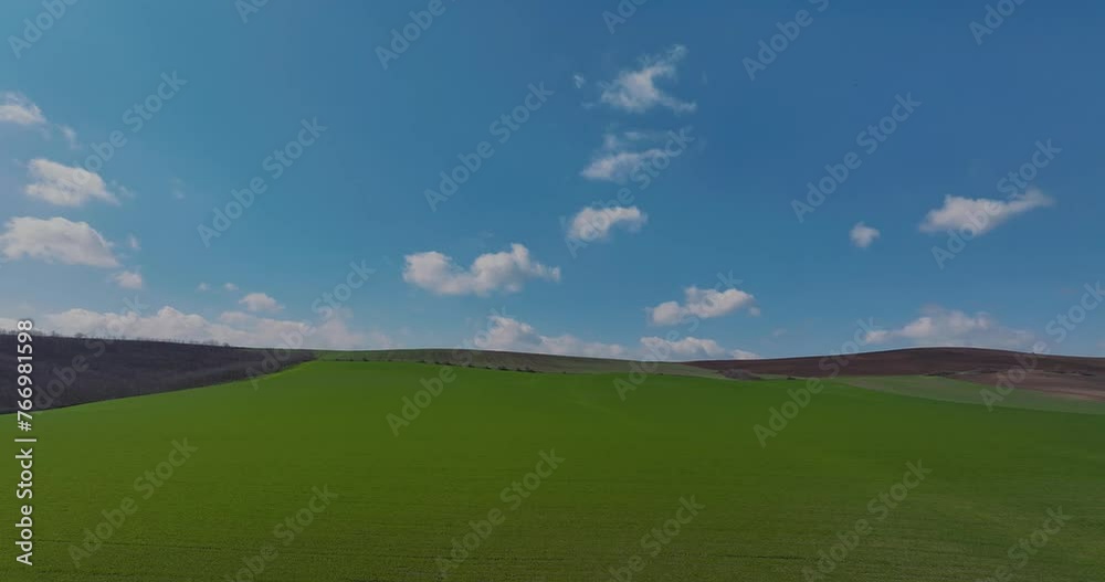 Aerial low shot vibrant green agricultural fields blue sky at the horizon, in the countryside on a spring sunny day Aerial low shot vibrant green agricultural fields blue sky at the horizon, in the countryside on a spring sunny day