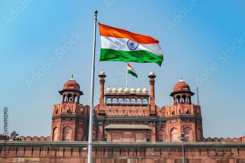 A majestic tricolor flag of India waving proudly against the backdrop of a clear blue sky, surrounded by iconic national landmarks such as the Red Fort.