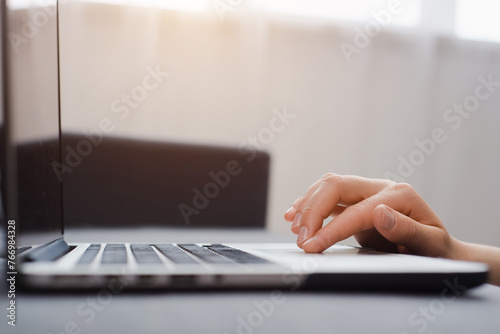 Close up of unrecognizable young caucasian woman using laptop, female hands typing, writing notes, studying languages, distance learning concept, checking email in morning, working at home