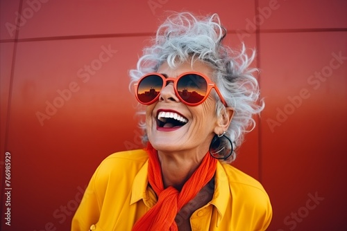Portrait of a happy senior woman in sunglasses against a red background