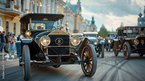 A procession of antique automobiles, with their headlights gleaming, parades down a city street, reviving the glory of early automotive history. © Chomphu
