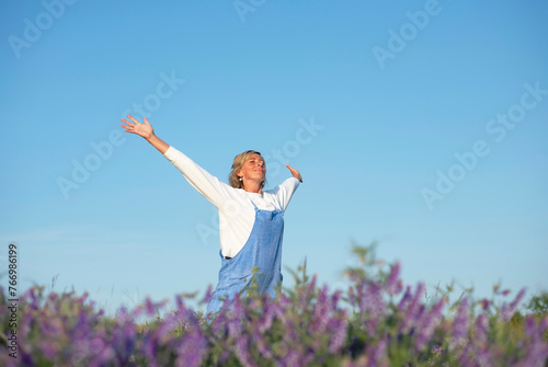 fröhliche junge Frau jubelt in einer Blumenwiese