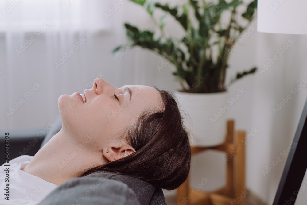 Close up of calm millennial woman lying relaxing on cozy couch in living room breathe fresh ventilated condition air. Happy young female renter rest on comfy sofa at home relieve negative emotions Close up of calm millennial woman lying relaxing on cozy couch in living room breathe fresh ventilated condition air. Happy young female renter rest on comfy sofa at home relieve negative emotions