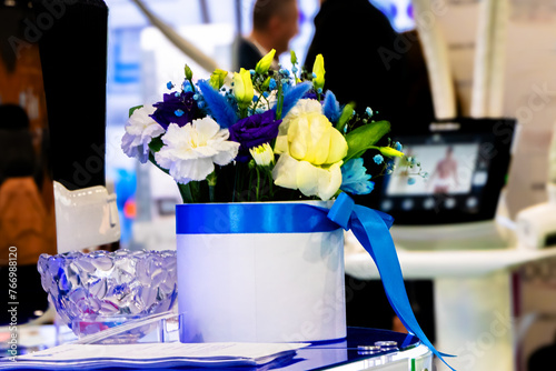 Table with a vase of flowers with a blue ribbon. The stage is set for a corporate business event.