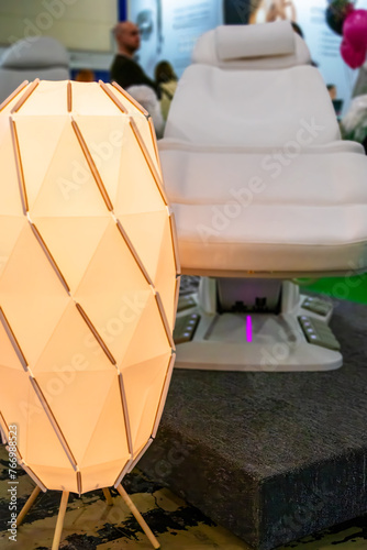 This is a modern vanity chair and white lamp set with a unique design. The lamp is a geometric shaped object with a white base and yellow light.