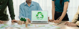 Recycle sign displayed on green business laptop while business team presenting green design to customer. ESG environment social governance and Eco conservative concept. Closeup. Delineation