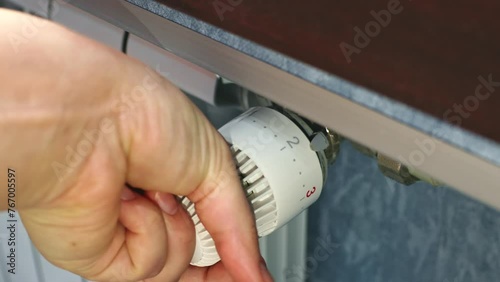 Female hands turning the heating adjusting radiator valve in a room close up photo
