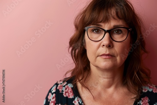 Portrait of a middle-aged woman with glasses on a pink background