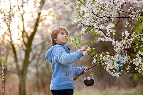 Beautiful blond child, boy, holding twig, braided whip made from pussy willow, traditional symbol of Czech Easter used for whipping girls and basket with eggs