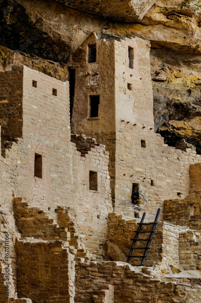 A detailed view of centuries-old Pueblo architecture, showcasing the intricate stonework nestled in a cliff face