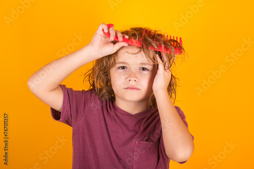 Tangled kids hair. Child with tangled blonde long hair tries to comb it. Hair portrait kid with a comb.