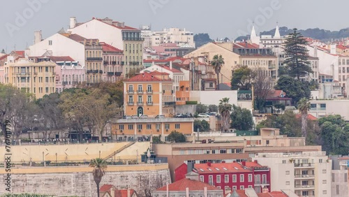Aerial view over the center of Lisbon to the viewpoint called Miradouro de Sao Pedro de Alcantara timelapse. Colorful houses on a hill. People in the park and cafe with tables. Portugal photo