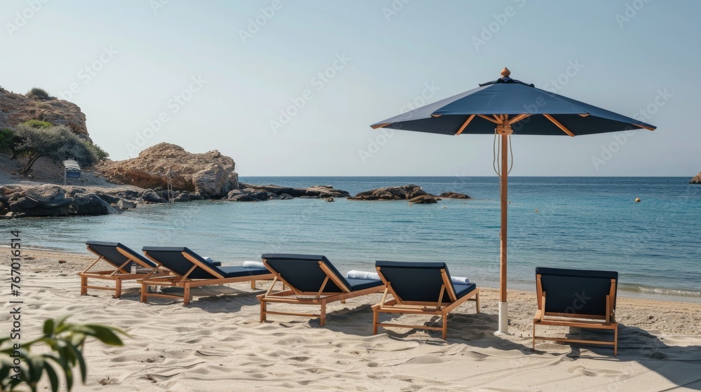 A set of navy sunbeds with wooden frames under an umbrella on the beach. 