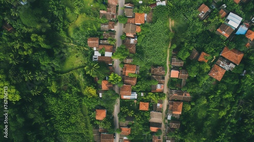 Top view of a small village with red tile roofs. The village is surrounded by lush green vegetation.