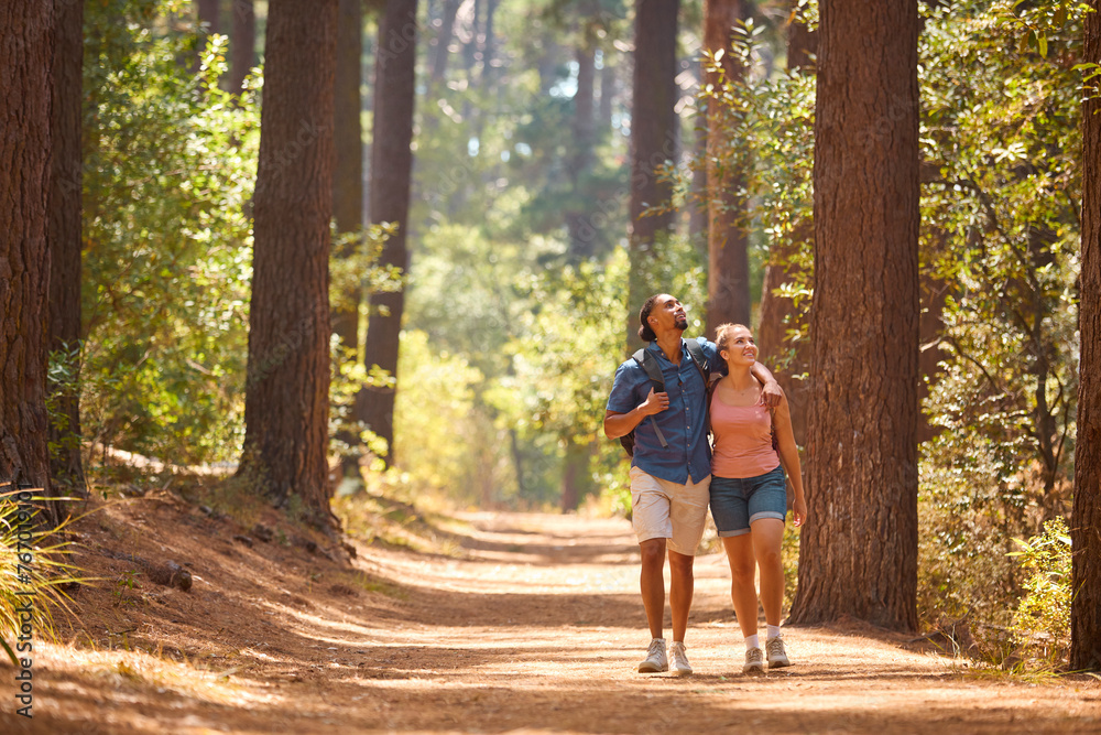 Fototapeta premium Loving Young Active Couple Wearing Backpacks Hiking Along Trail Through Countryside