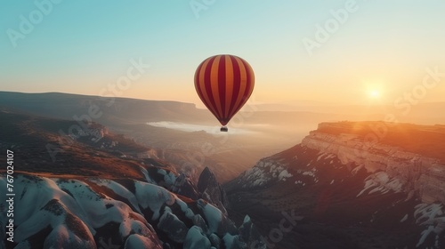 Hot air balloon over snowy mountains at sunrise.