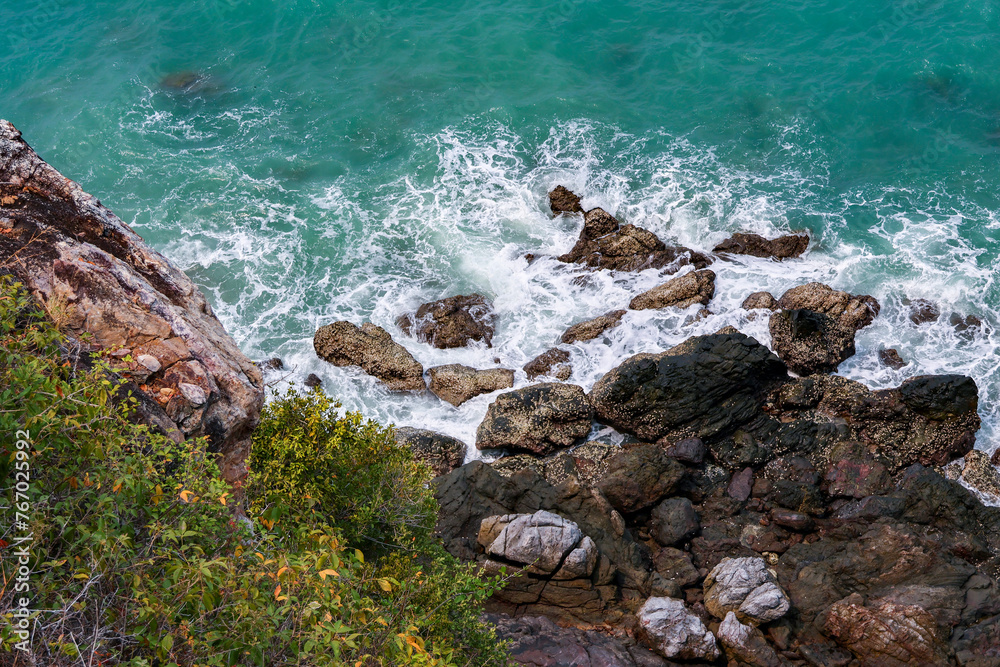 high-angle landscape of rocks by the sea The view from the mountain in the island with the cool breeze, green trees and the blue sea. The air is nice and refreshing in the summer in Thailand.