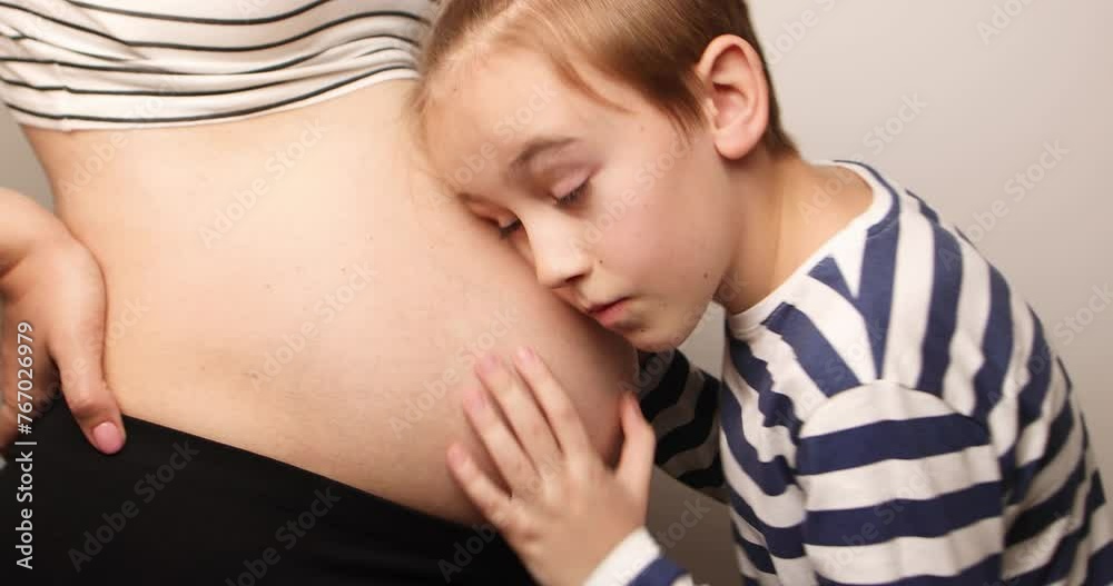 Little boy looking at her mother pregnant tummy. Pregnant mother and son spending time together at home. Pregnancy, family, parenthood, preparation and expectation concepts. Little boy looking at her mother pregnant tummy. Pregnant mother and son spending time together at home. Pregnancy, family, parenthood, preparation and expectation concepts.