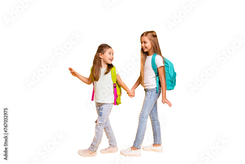 Full length body size view of two nice attractive cheerful smart clever pre-teen girls with colorful backpacks holding hands back to school isolated over bright vivid shine yellow background photo