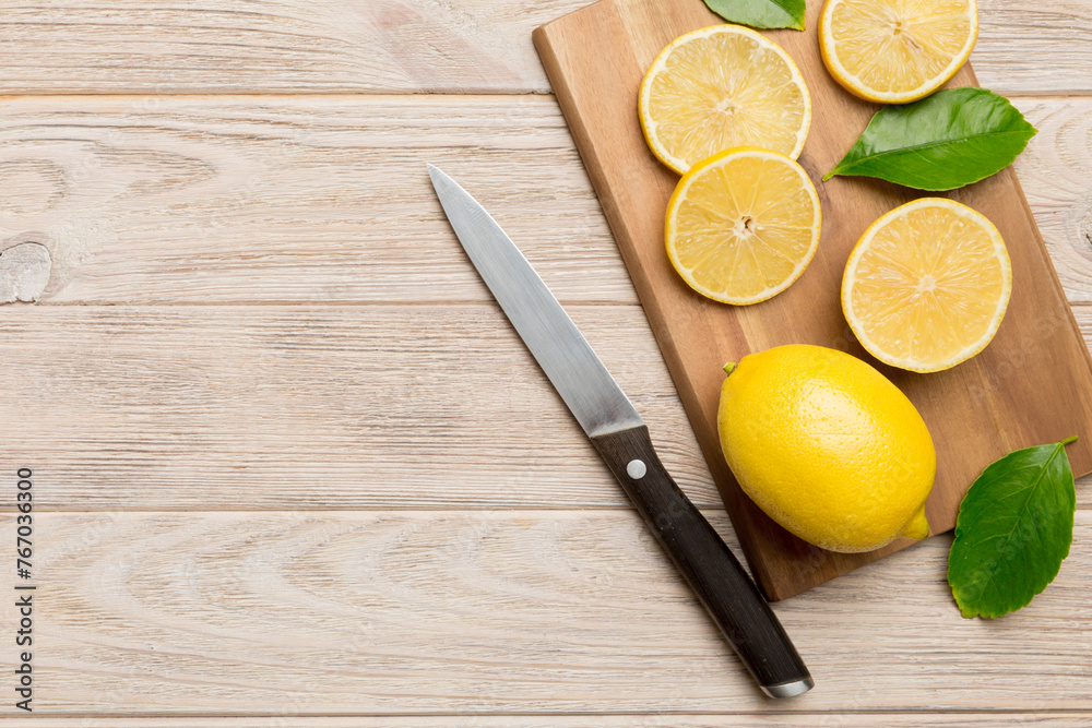 Top view with copy space for fresh and ripe lemons on cutting board. Healthy food background. Elegant background of lemon and lemon slices with squeezer and knife colored background Top view with copy space for fresh and ripe lemons on cutting board. Healthy food background. Elegant background of lemon and lemon slices with squeezer and knife colored background