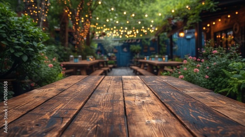   A wooden table sits in front of a lush forest filled with numerous green plants and ceiling-mounted lights