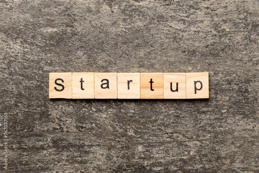 Fototapeta premium startup word written on wood block. startup text on table, concept