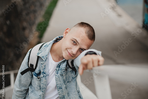 Фотография A young man in a blue jacket and white shirt is smiling and leaning against a white railing
