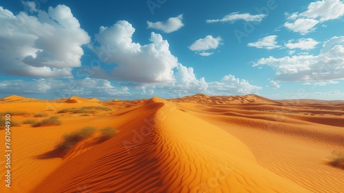  A serene desert panorama boasts undulating sand dunes beneath a cerulean sky adorned with fluffy white clouds, while tiny shrubs accent