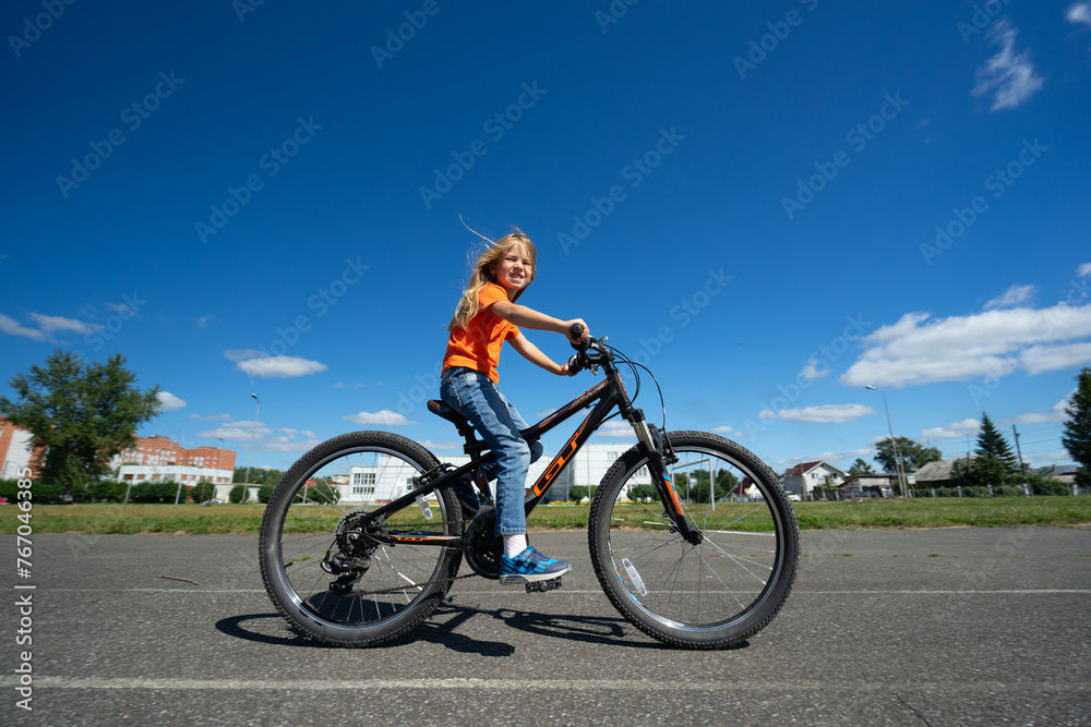 girl in an orange sweater rides a bicycle