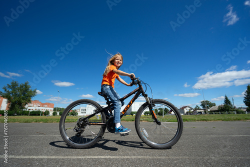 Fototapeta Naklejka Na Ścianę i Meble -  girl in an orange sweater rides a bicycle