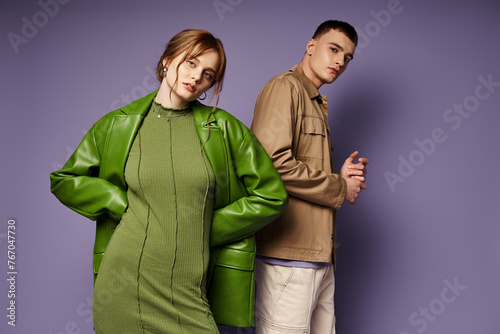 appealing loving couple in vibrant colorful attires looking at camera on purple background