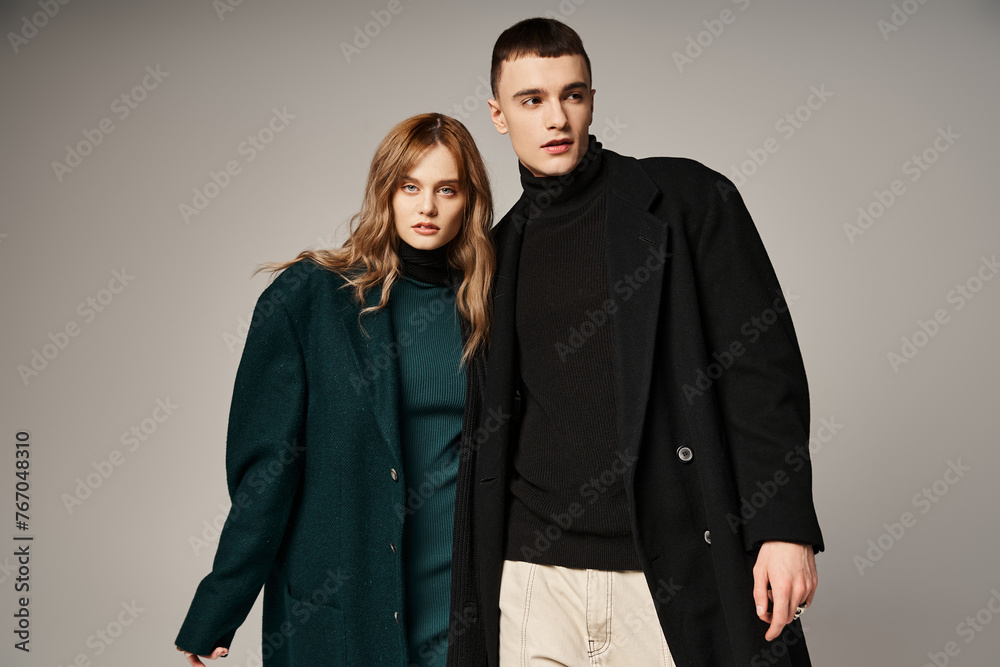 appealing man in coat posing lovingly next to his beautiful girlfriend who looking at camera appealing man in coat posing lovingly next to his beautiful girlfriend who looking at camera