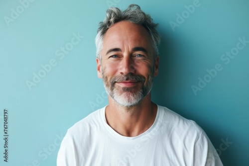 Portrait of handsome mature man with grey hair and beard on blue background
