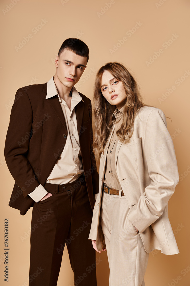 elegant young woman in stylish suit posing with her handsome boyfriend and looking at camera elegant young woman in stylish suit posing with her handsome boyfriend and looking at camera