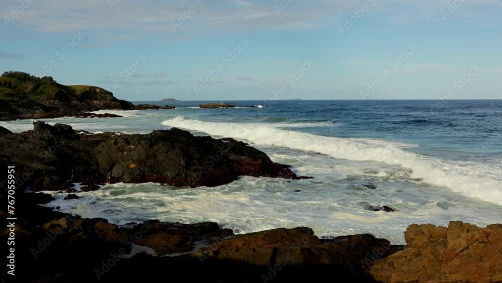 Pacific ocean view of wave crashing on rocky coastal headland with blue sky in background. Pacific ocean view of wave crashing on rocky coastal headland with blue sky in background.