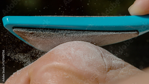 MACRO, DOF: Macro shot of a foot being exfoliated with a blue pedicure tool.