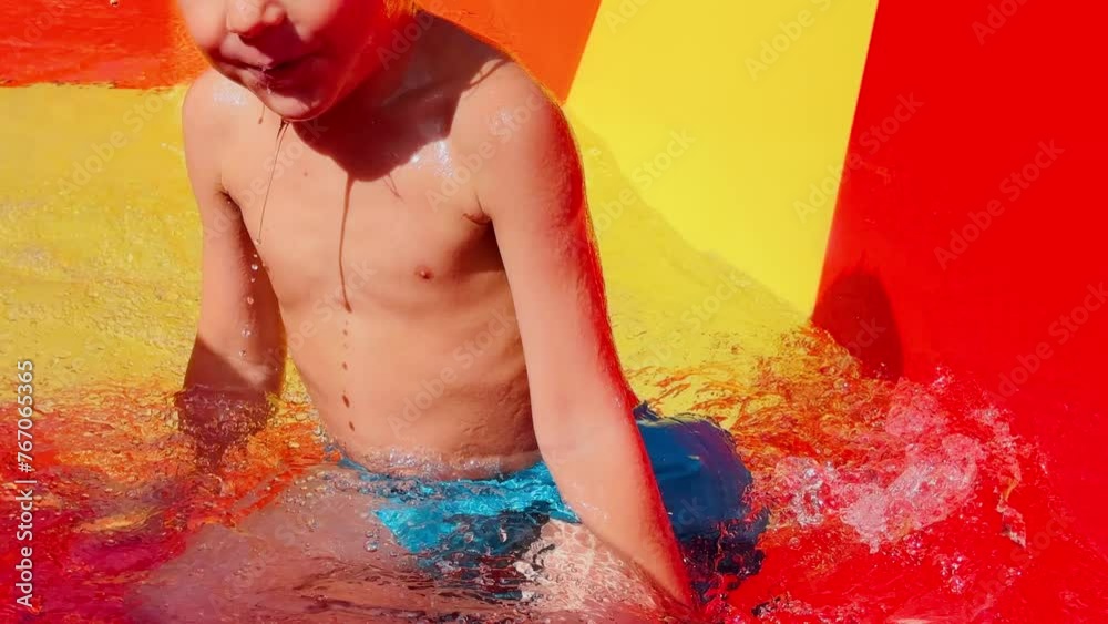 Young boy slides down a water slide with splashes around him