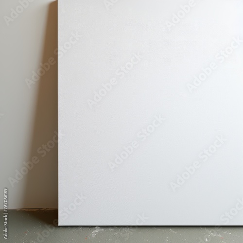 A blank canvas stands on the floor, there is a white wall behind, half of the canvas is visible, canvas mockup