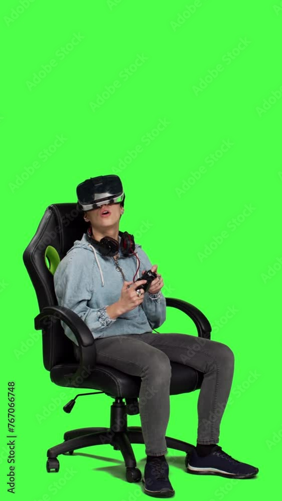 Side view Woman celebrating her championship win with vr headset and controller, playing video games cyber space tournament against greenscreen backdrop. Gamer feeling cheerful about victory. Camera A Side view Woman celebrating her championship win with vr headset and controller, playing video games cyber space tournament against greenscreen backdrop. Gamer feeling cheerful about victory. Camera A
