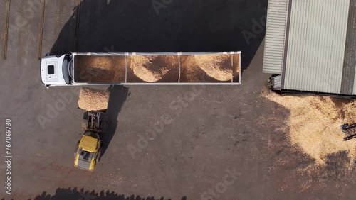 Loader Tractor Loading Wood Chips Into Trailer Truck At Sawmill Factory. topdown shot
