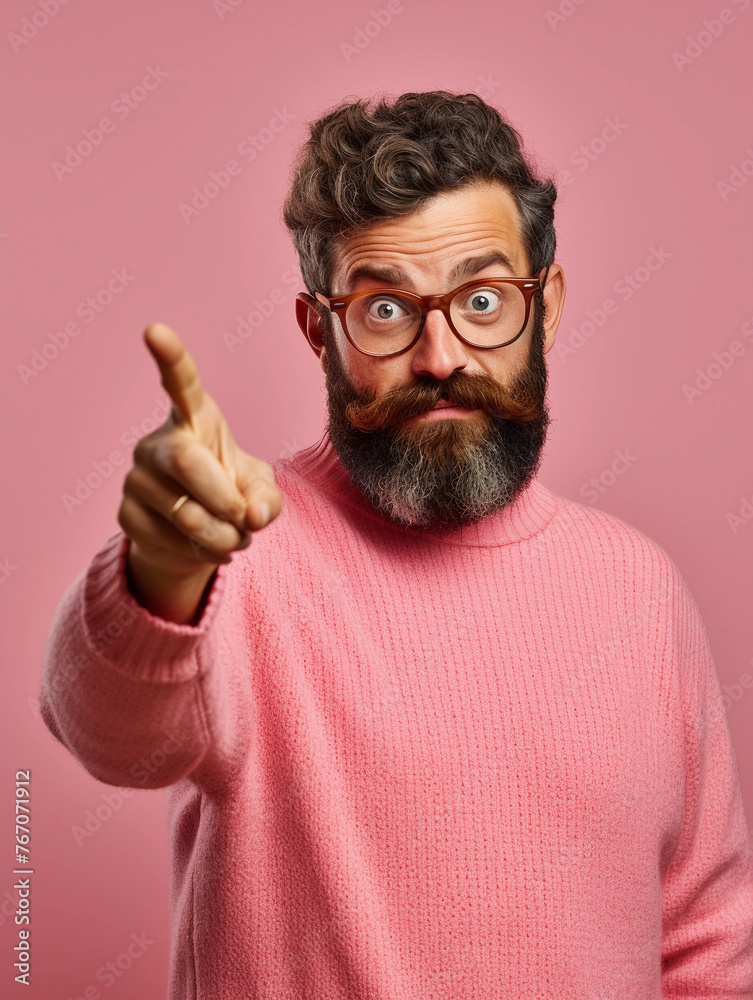 Portrait of a man wearing glasses with a beard gesturing with a finger that everything is fine or showing okey with a finger dressed in a pink sweater isolated on a pink background. Portrait of a man wearing glasses with a beard gesturing with a finger that everything is fine or showing okey with a finger dressed in a pink sweater isolated on a pink background.