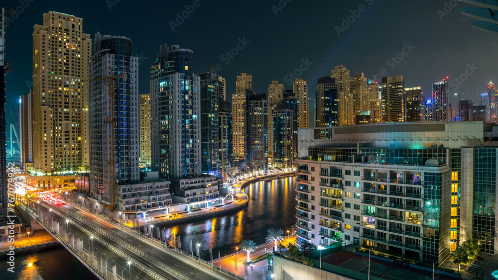 Dubai Marina at night timelapse with light trails of boats on the water and cars, Dubai, UAE