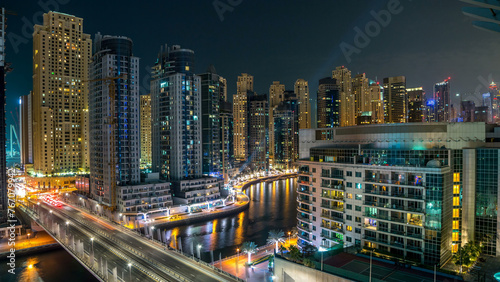 Dubai Marina at night timelapse with light trails of boats on the water and cars, Dubai, UAE © neiezhmakov