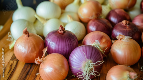 A bunch of onions of different colors are on a wooden table. The onions are of various sizes and colors, including white, red, and purple. Concept of abundance and variety