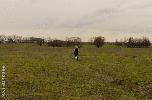 spring field in the village with a cyclist © Farkhad