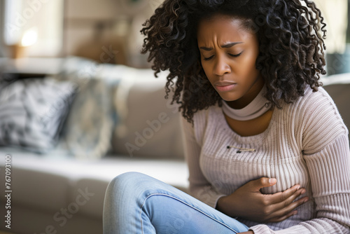 Young woman with abdominal pain holding her stomach. 
