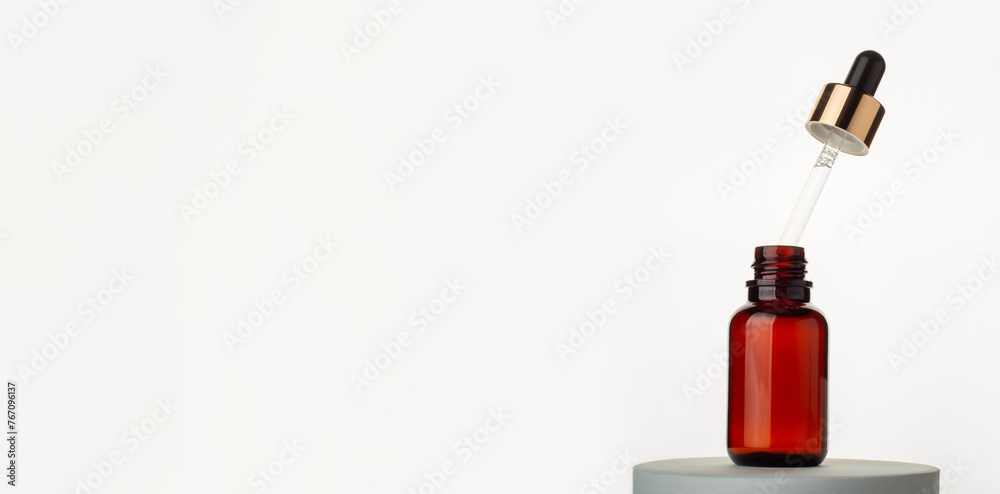 Obraz premium Cosmetic glass brown bottle and pipette with essential oil on white background.