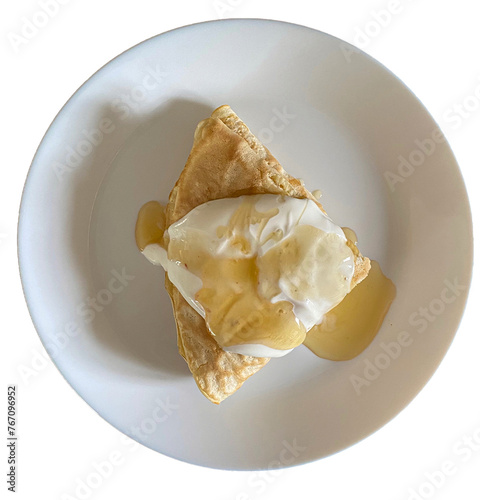 Słodki naleśnik  z serem na białym talerzu polany śmietaną i miodem. Widok z góry. Przezroczyste tło. Domowe jedzenie.