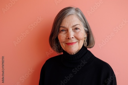 Portrait of a smiling senior woman with gray hair on a pink background