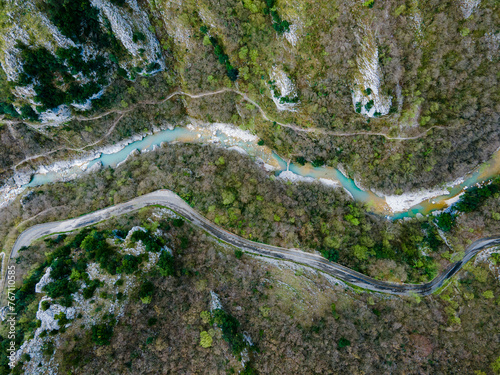 View from above of a narrow river behind a mountain forest